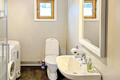 Salle de bain avec WC, lavabo, machine à laver et miroir dans une yourte de vacances à Lysøysundet, Suède.