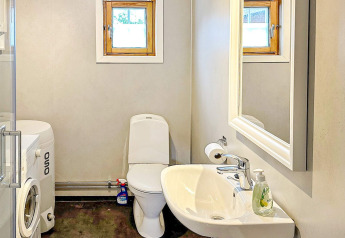 Badeværelse med toilet, håndvask, vaskemaskine og spejl i en 4-personers feriehytte i Lysøysundet, Sverige.