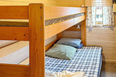 Cozy wood-paneled bunk bed room with plaid beddings and pillows in a 4-person holiday home in Lysøysundet, Sweden.