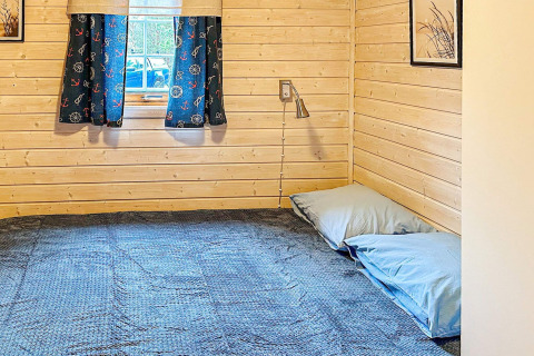 Gezellige houten slaapkamer in een vakantiehuis in Lysøysundet, Zweden, met blauwe gordijnen en laag bed.