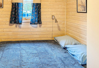 Accogliente camera da letto in legno in una casa vacanze a Lysøysundet con tende blu e letto basso.