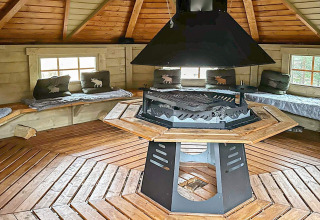 Interieur van een knusse ronde yurt met houten banken, kussens en centrale haard in Lysøysundet, Zweden.