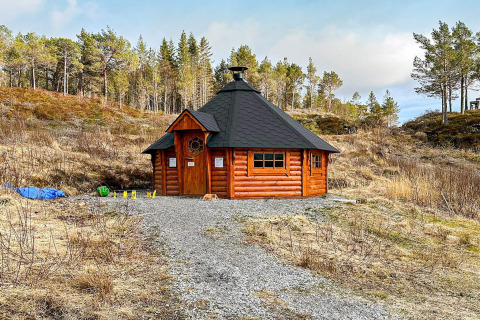 A 4-person holiday wooden yurt in Lysøysundet, Sweden, set amidst grassy land and forest trees.