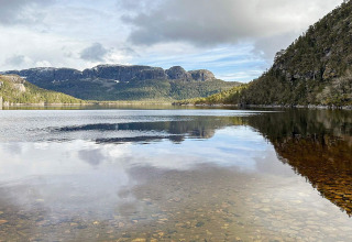 Vista panoramica di lago e montagne da una yurta a Lysøysundet, Svezia, con acqua limpida e riflessi.