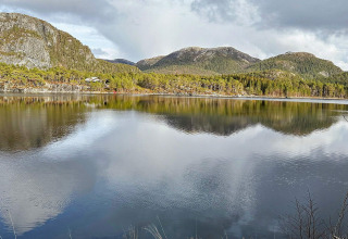 Vista panorámica de montañas, bosque y lago desde una yurta en Lysøysundet, Suecia en día nublado.