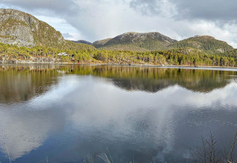Prachtig uitzicht op bergen, bos en meer vanaf een yurt bij Lysøysundet, Zweden op een bewolkte dag.