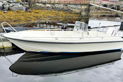 Petite embarcation à moteur amarrée près d’une yourte à Lysøysundet, Suède, avec reflets calmes.