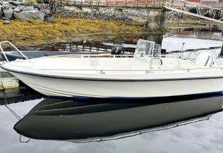 Kleine motorboot aangemeerd bij een yurt in Lysøysundet, Zweden, met kalme waterreflecties.