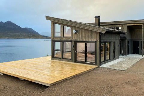 Moderne vakantiewoning in Stokmarknes met groot houten terras en uitzicht op het meer en de bergen.