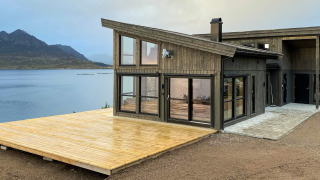 Casa de vacaciones moderna en Stokmarknes con terraza grande de madera y vista al lago y montañas.