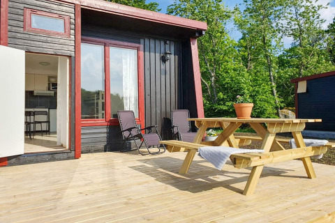 Terraza soleada en casa de vacaciones 4 estrellas en Karlskrona con mesa de picnic y vistas al bosque.