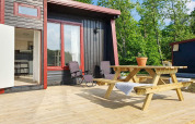 Sonnige Terrasse am 4-Sterne-Ferienhaus in Karlskrona mit Picknicktisch, Liegestühlen und Waldblick.