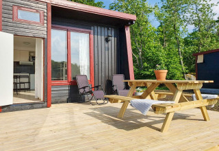 Zonnig terras bij 4-sterren vakantiehuis in Karlskrona met picknicktafel, ligstoelen en boszicht.