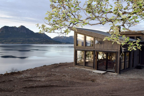 Moderne lodge kaldet '5 star holiday home in stokmarknes' ved søbred med bjerge i baggrunden i Sverige.