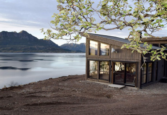 Modern lodge '5 star holiday home in stokmarknes' by a lake, with mountain views in Sweden in springtime.