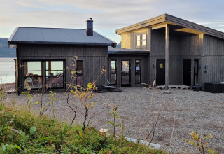 Moderne feriebolig ved vandet i Stokmarknes, Sverige, med sort træfacade og store vinduer.