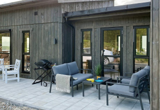 Udendørs terrasse på den 5-stjernede feriebolig i Stokmarknes, Sverige, med komfortable havemøbler.