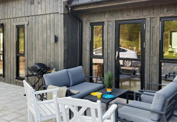 Gemütliche Terrasse eines 5-Sterne-Ferienhauses in Stokmarknes, Schweden, mit Lounge-Möbeln und Grill.
