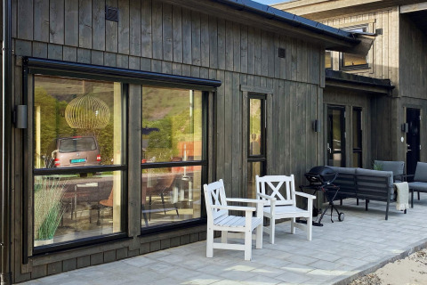 Udendørsområde ved lodge i Stokmarknes, Sverige, med træmøbler og store vinduer der reflekterer naturen.