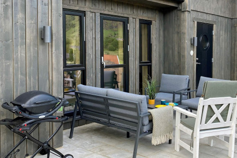 Udendørs terrasse ved femstjernet feriebolig i Stokmarknes, Sverige, med grill, borde og stole.
