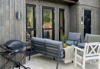 Terraza de casa vacacional cinco estrellas en Stokmarknes, Suecia, con barbacoa y mobiliario de exterior.