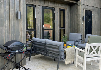 Patio of 5 star holiday home in Stokmarknes, Sweden, featuring grill, grey seating, and outdoor decor.