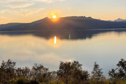 Smuk solnedgang over et stille vand med bjergsilhuetter, set fra lodge '5 star holiday home in stokmarknes' i Sverige