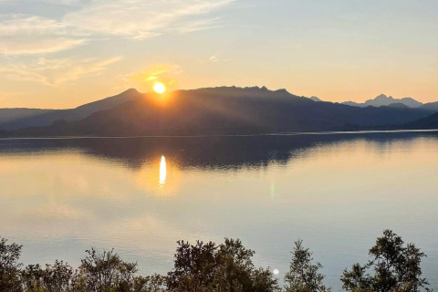 Zonsondergang boven een kalm meer met bergen vanaf 5 star holiday home in stokmarknes, Zweden.
