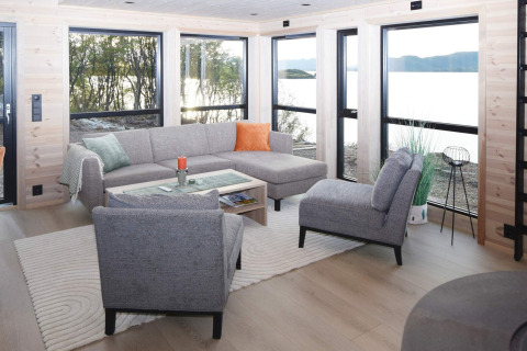 Salón moderno en la casa vacacional de 5 estrellas en Stokmarknes, Suecia, con grandes ventanales y vista.