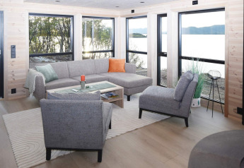 Salon moderne de la maison de vacances 5 étoiles à Stokmarknes, Suède, avec grandes fenêtres et vue nature.
