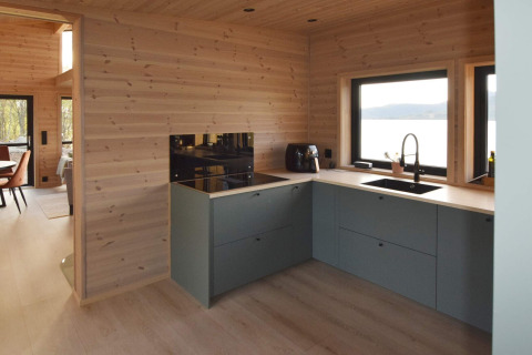 Cuisine moderne dans une maison de vacances 5 étoiles à Stokmarknes, Suède, vue sur le lac et murs en bois.