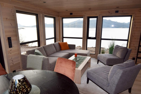 Modernes Wohnzimmer in einer Lodge mit Panoramafenstern und Seeblick in Stokmarknes, Schweden.