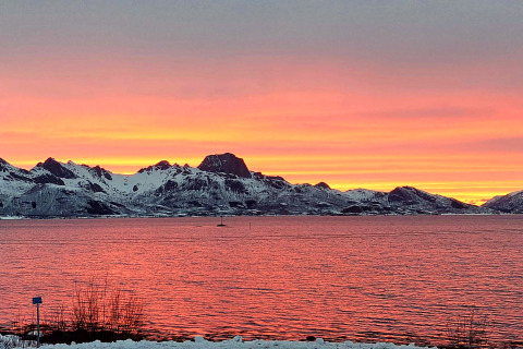 Smuk solnedgang over sneklædte bjerge og vand, set fra 5 star holiday home in Stokmarknes, Sverige.