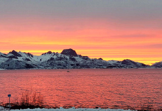 Smuk solnedgang over sneklædte bjerge og vand, set fra 5 star holiday home in Stokmarknes, Sverige.