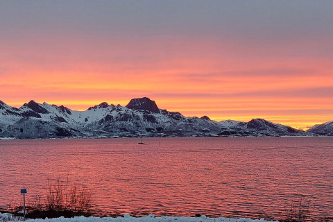 Adembenemende zonsondergang over besneeuwde bergen en water vanuit 5 star holiday home in Stokmarknes, Zweden.