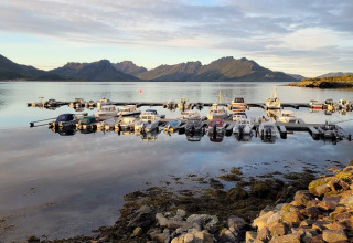 Boote liegen im ruhigen Wasser vor der Kulisse der Berge bei der 5-Sterne-Ferienwohnung in Stokmarknes.
