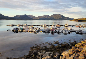 Barcos atracados en aguas tranquilas frente a la casa de vacaciones de 5 estrellas en Stokmarknes, Suecia.
