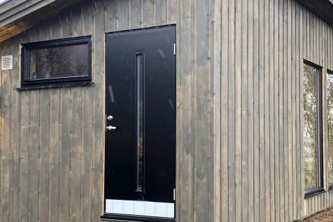 Puerta negra con ventana alargada y ventanas laterales en casa rural 5 star holiday home in Stokmarknes, Suecia.