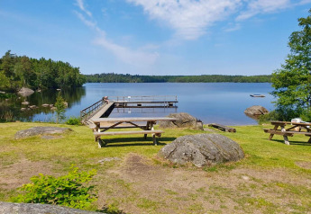 Picknicktafels en pier aan een rustig meer gezien vanaf een 4-sterren vakantiehuis in Karlskrona.