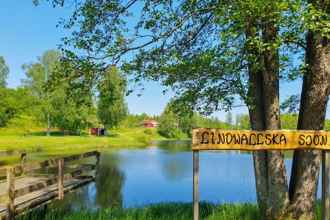 Vista pintoresca del lago Lindwallska, letrero y casa de vacaciones en Karlskrona, Suecia, rodeada de naturaleza.