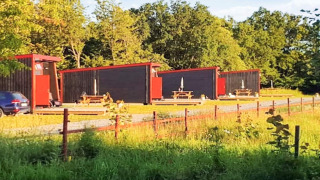 Moderne huisjes met rode randen in KARLSKRONA, omgeven door groen en picknicktafels in de zon.