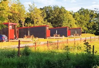 Chalets modernes aux bordures rouges à KARLSKRONA, entourés de verdure et de tables de pique-nique.