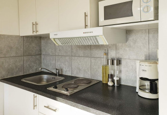 Moderne kitchenette met kookplaat, spoelbak, magnetron en koffiezetapparaat in een vakantiehuis te Karlskrona.