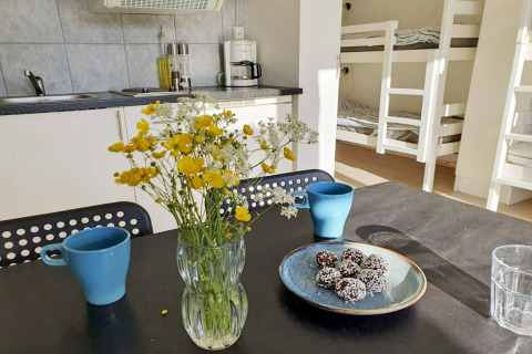 Et hyggeligt køkken i en feriehytte i Karlskrona, Sverige, med blomster, kopper og snacks på bordet.