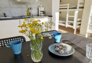 Gemütliche Küchenszene in einer Ferienhütte in Karlskrona, Schweden, mit Blumen und Tassen am Tisch.
