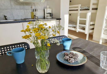 Knusse keuken in een vakantiehuisje in Karlskrona, Zweden, met bloemen, mokken en lekkers op tafel.