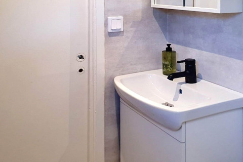 Lavabo de salle de bain moderne avec robinet noir et distributeur de savon dans une maison de vacances à Karlskrona, Suède.