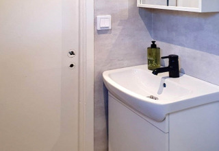 Moderne badkamerwastafel met zwarte kraan en zeepdispenser in een vakantiehuis in Karlskrona, Zweden.