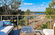 Terrasse moderne d'une maison de vacances à VÄDDÖ, Suède, surplombant la nature, les rochers et l'eau.