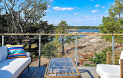 Terrasse moderne d'une maison de vacances à VÄDDÖ, Suède, surplombant la nature, les rochers et l'eau.